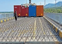 shipping containers iron spikes and coils of barbed wire seal attock bridge as two law enforcement personnel stand guard ahead of a pti protest march photo ppi