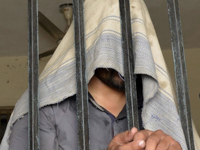 this photo taken on april 27 2014 shows a handcuffed pakistani suspect in connection with the murders of three homosexual men standing in a lockup at a police station in lahore photo afp