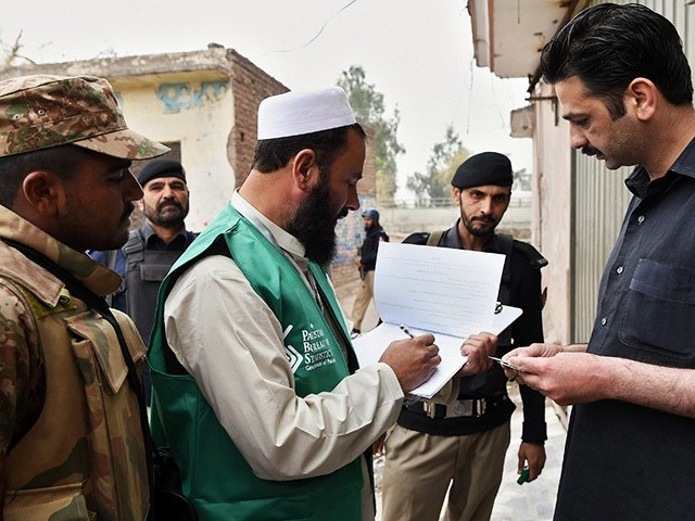 an official from the pakistan bureau of statistics collects information from a resident during a census as security personnel guard them in peshawar on march 15 2017 photo afp