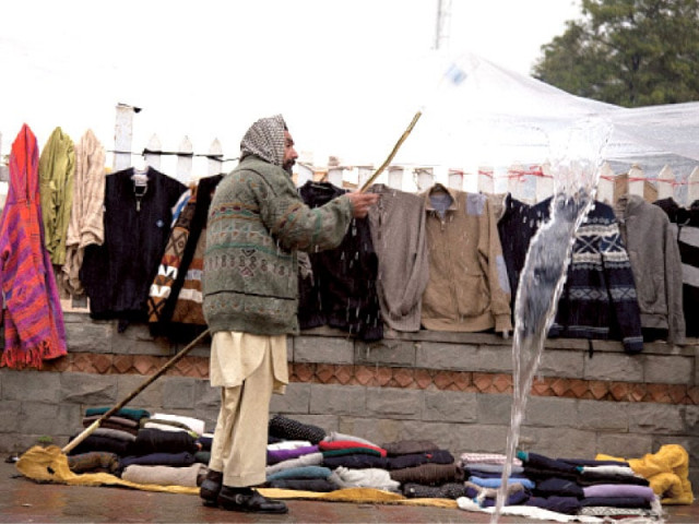 a shopkeeper drains rainwater from his canopy at his small stall selling sweaters in aapbara market in islamabad on friday photo myra iqbal express a shopkeeper drains rainwater from his canopy at his small stall selling sweaters in aapbara market in islamabad on friday photo myra iqbal express