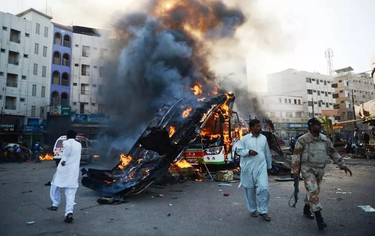 security officials walk beside a burning passenger bus after an explosion in karachi photo afp security officials walk beside a burning passenger bus after an explosion in karachi photo afp