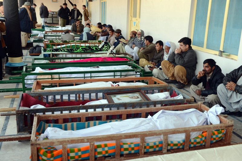 shia muslim mourners sit beside the coffins of blast victims at a mosque following overnight twin suicide bombings in quetta on january 11 2013 photo afp