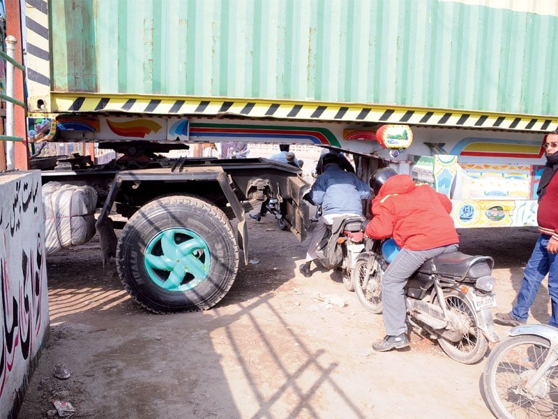 motorcyclists find a unique way to get passed a barricade at soan bridge while commuters were forced to walk beyond this point photo waseem nazir express