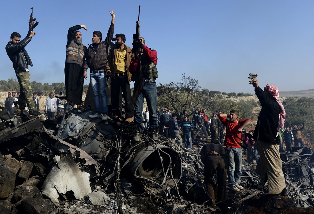 syrian rebels celebrate on top of the remains of a syrian government fighter jet which was shot down at daret ezza on the border between provinces of idlib and aleppo photo afp francisco leong