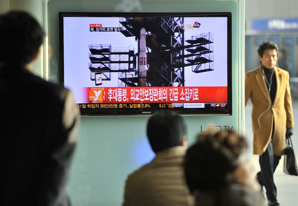 travellers watch a tv screen broadcasting news on north korea 039 s rocket launch at a railway station in seoul on december 12 2012 photo afp