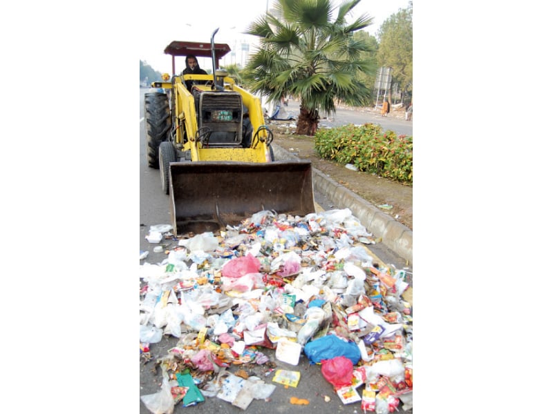 a crane lifts a container blocking access to the red zone top a bulldozer collects trash on the road photo muhammad javaid express