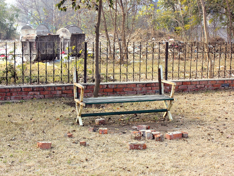 garbage strewn right next to a park top a missing manhole presenting danger to children playing nearby photo waqas naeem express