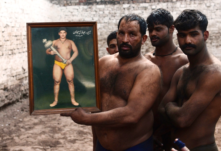 wrestlers hold a picture of a famous jhara wrestler during training at a practise ring in lahore photo afp