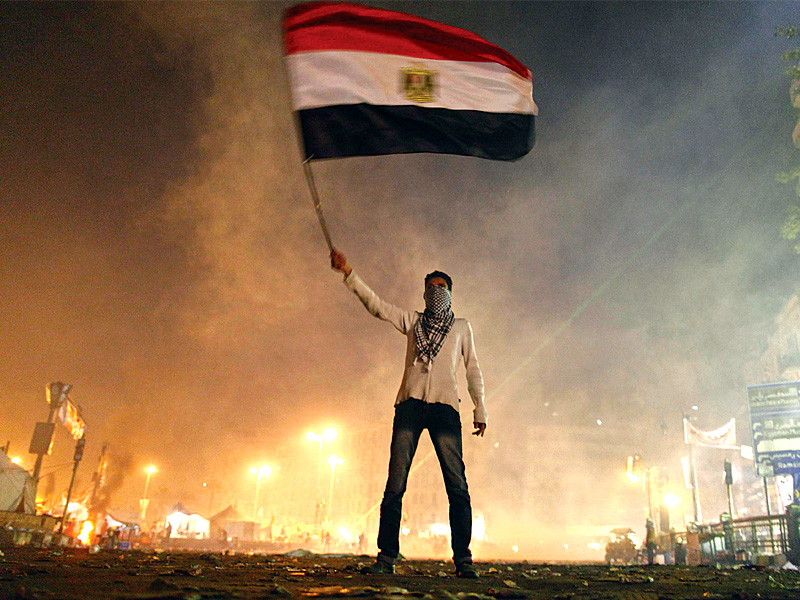 a protester waves the egyptian flag in the midst of tear gas fired by riot police in tahrir square photo afp
