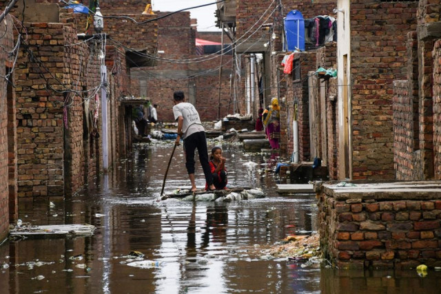a man and a girl use a makeshift raft as they cross a flooded street following rains during the monsoon season in hyderabad pakistan august 24 2022 reuters
