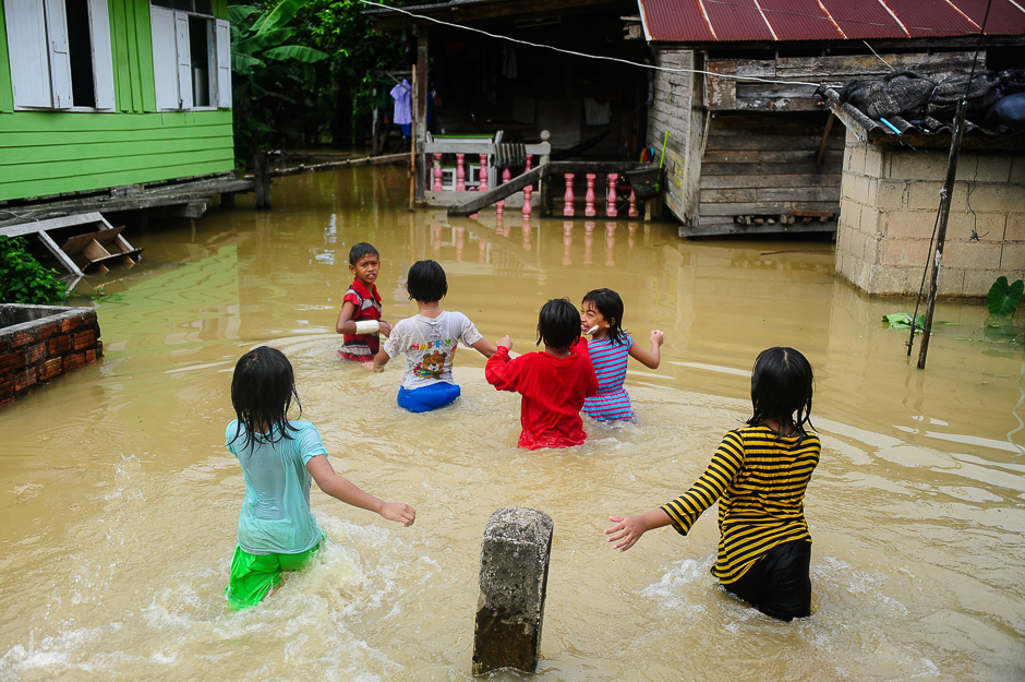 Children play near houses inundated by floodwaters after heavy rains in the Rangae district of the southern province of Narathiwat. PHOTO: AFP