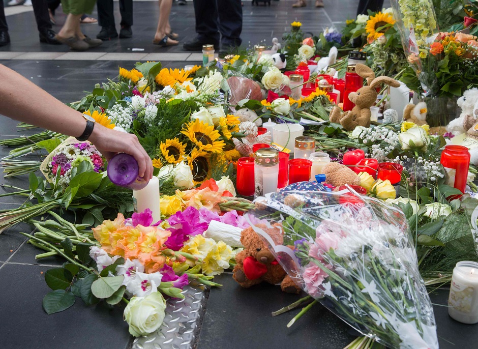 A woman lights a candle at a makeshift memorial for an eight-year-old boy who died when a man pushed him and his mother in front of a train in Germany's Frankfurt railway station. PHOTO: AFP