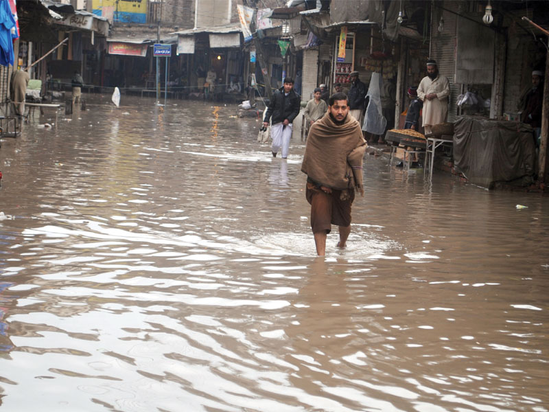 a man walks through the standing water at peepal mandi peshawar photo muhammad iqbal express