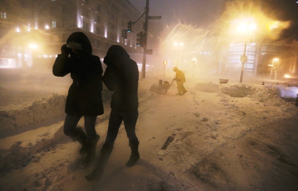 boston ma people walk through a driving snow as a worker clears a sidewalk in the back bay neighborhood on february 8 2013 photo afp