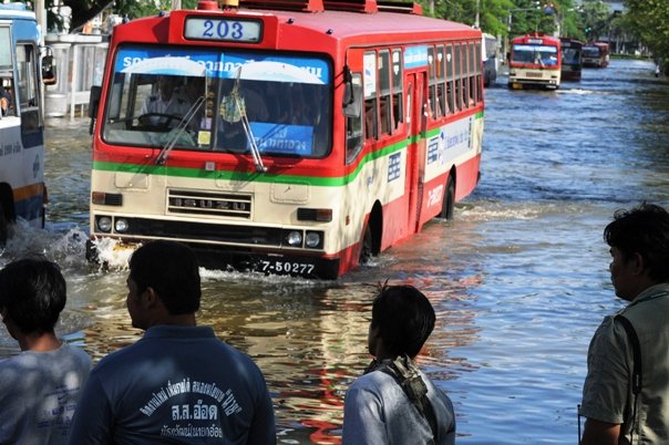 thai men watch on buses travel through floodwaters in bangkok photo afp