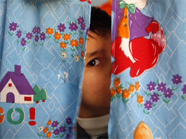an autistic child peers from between curtains at the consulting centre for autism in amman jordan photo reuters