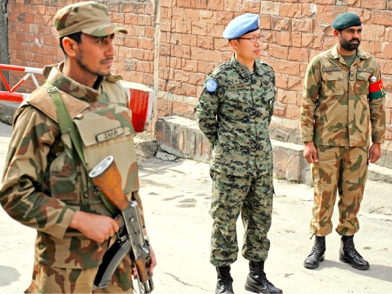 a member of un military observer group c stands with pakistani soldiers at the office of the unmogip during an anti india demonstration in muzffarabad photo reuters