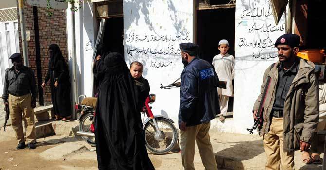 a burqa clad woman holds her child as she walks past police men outside a polio vaccination center in karachi on january 8 2013 photo afp file