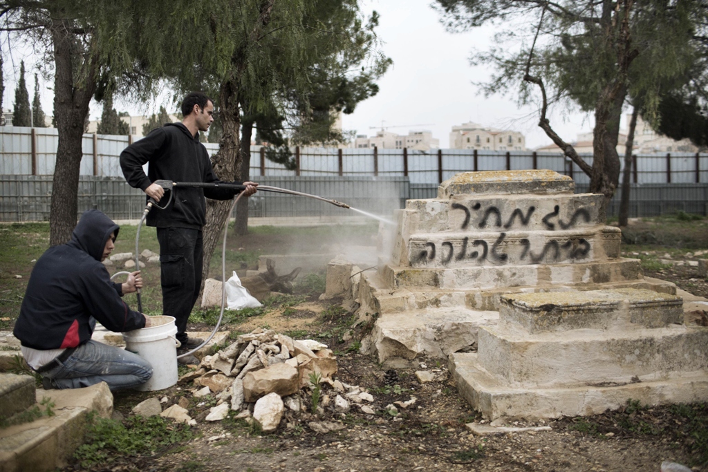 municipal workers erase the words quot price tag quot spray painted in hebrew on a gravestone at the mamun allah cemetery an old muslim cemetery in jerusalem on february 14 2013 photo afp