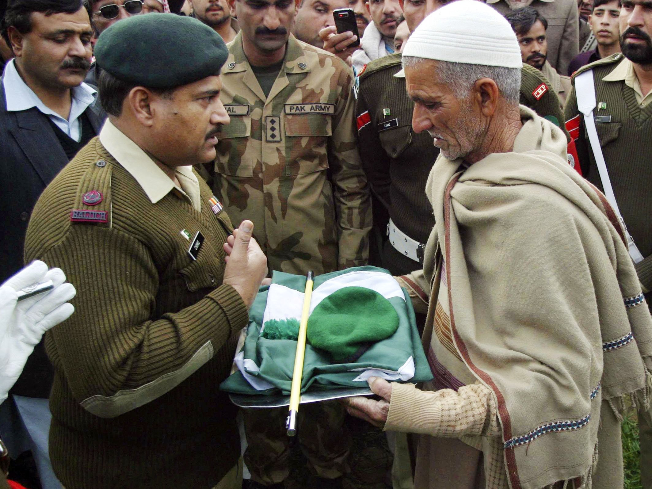 a military official hands over a pakistan military cap stick and national flag to the father of pakistani soldier muhammad akhlaq whom the pakistan military said was killed by indian soldiers while crossing into the indian side of kashmir photo reuters