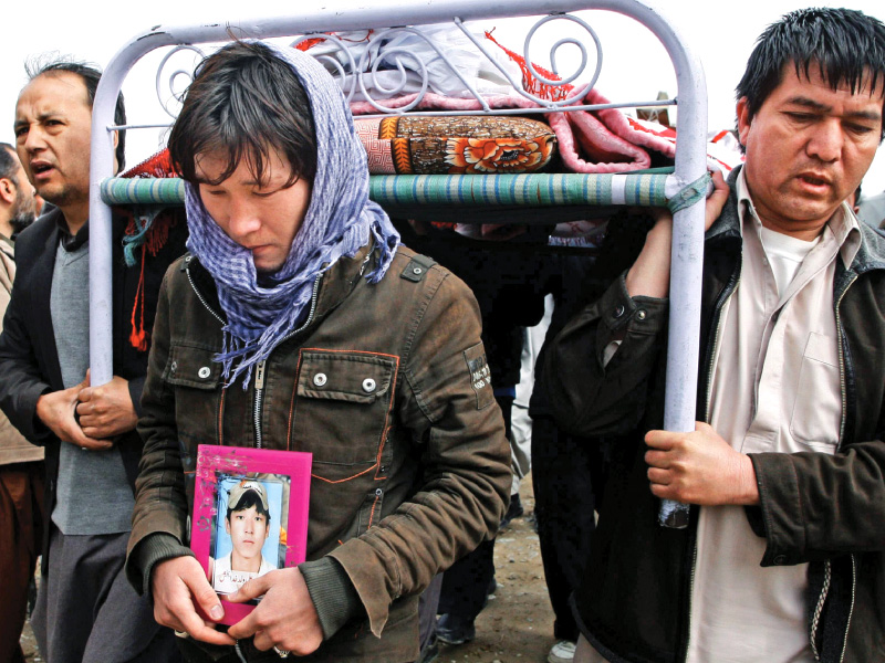 a man holds a photograph of his brother who was killed in saturday s bomb attack as he walks in front of his coffin during a funeral in quetta on wednesday photo reuters