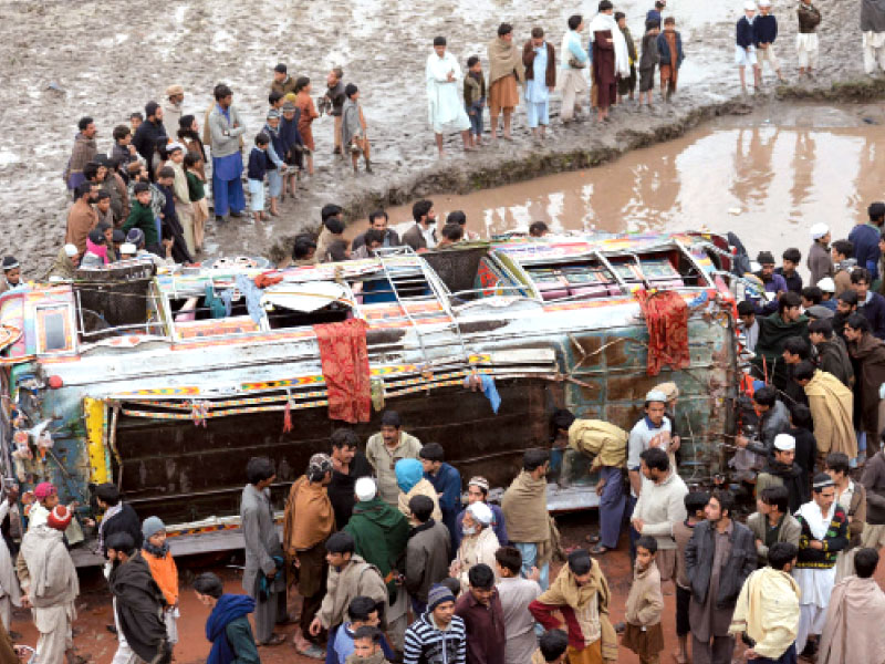 a crowd surrounds the passenger bus that fell into a canal in badhu samarbagh on friday afternoon photo sameer raziq express