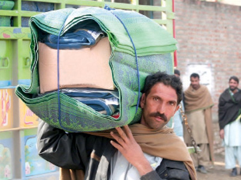 an internally displaced person from jalozai camp carrying relief items photo file