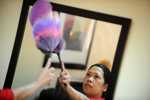 a filipina maid cleans a mirror during a government mandated crash course in domestic duties in manila on september 14 2011 photo afp file