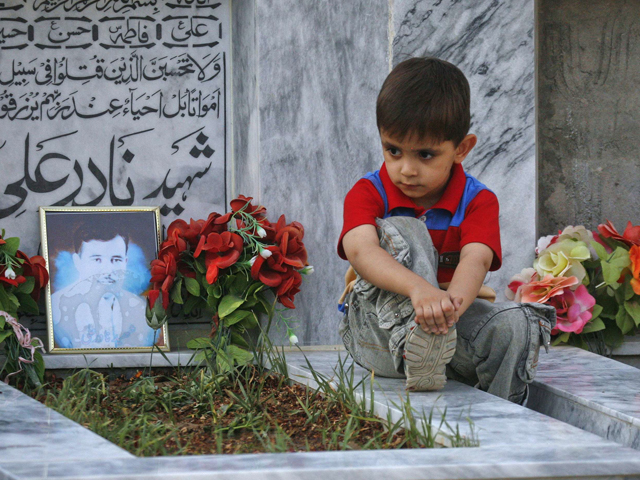 five year old sahil hazara sits on the grave of his brother nadir ali who was killed by unidentified gunmen at the hazara graveyard in mehrabad quetta photo reuters