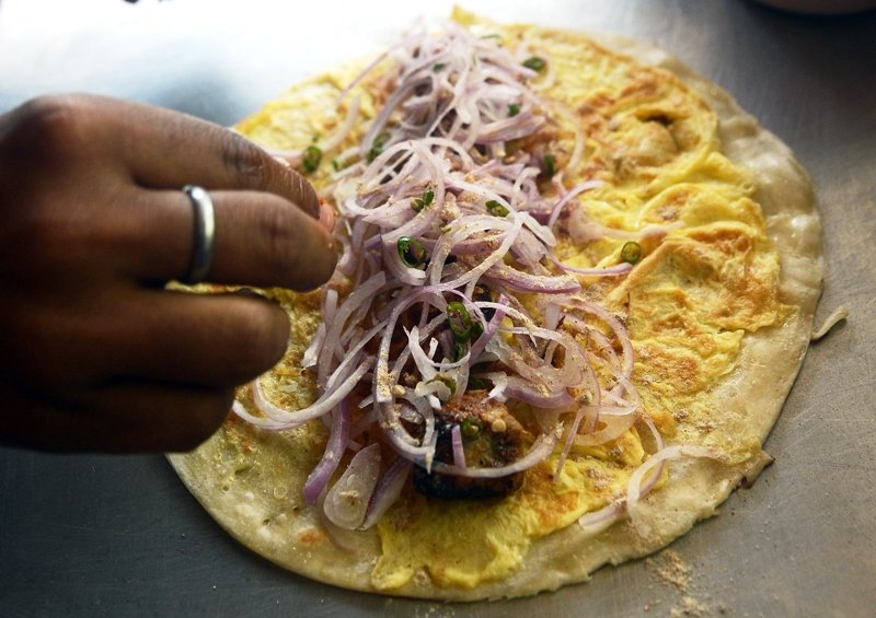 this picture taken on february 26 2013 shows an indian arranging onions on an egg wrap at the fast food chain hangla in mumbai photo afp