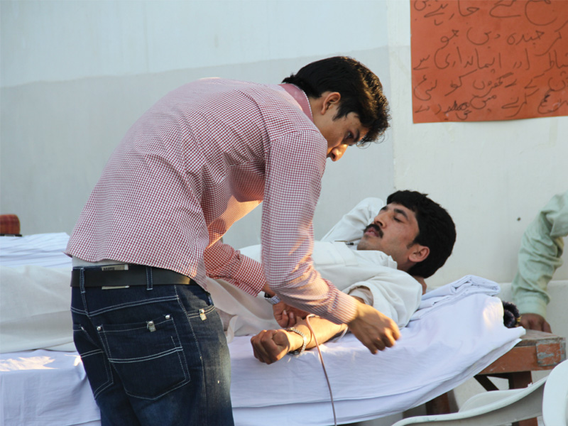 a man donates blood at a camp