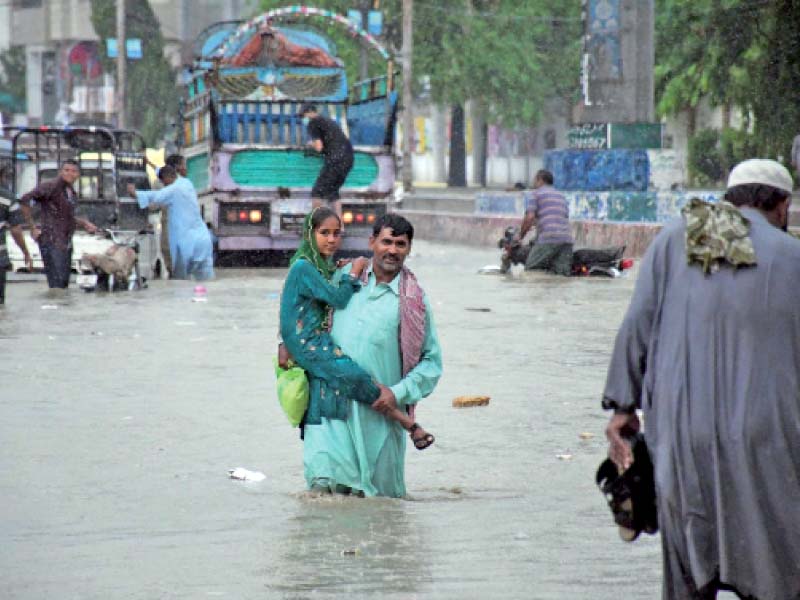 a man carrying his daughter wades through a flooded street in karachi as rain lashed the metropolis for the second consecu tive day on friday photo online