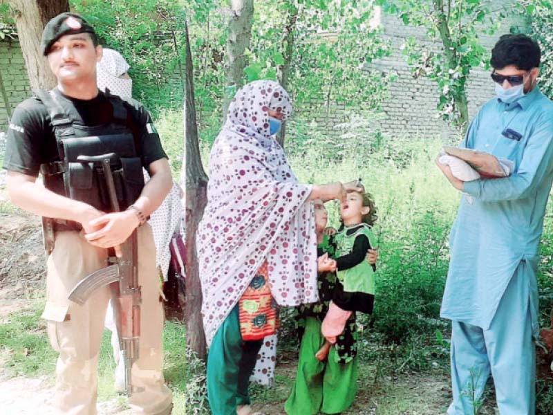 a policeman stands guard as health department workers administer polio drops to children during the inoculation drive in swabi district photo express