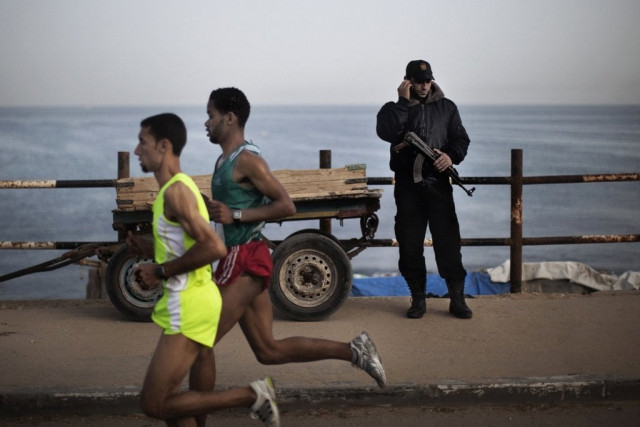 a picture taken on may 5 2011 shows a hamas policeman talking on the phone as palestinian olympic athlete nader masri l and a fellow runner speed along the waterfront in gaza city as they compete in the gaza strip 039 s marathon a picture taken on may 5 2011 shows a hamas policeman talking on the phone as palestinian olympic athlete nader masri l and a fellow runner speed along the waterfront in gaza city as they compete in the gaza strip 039 s marathon