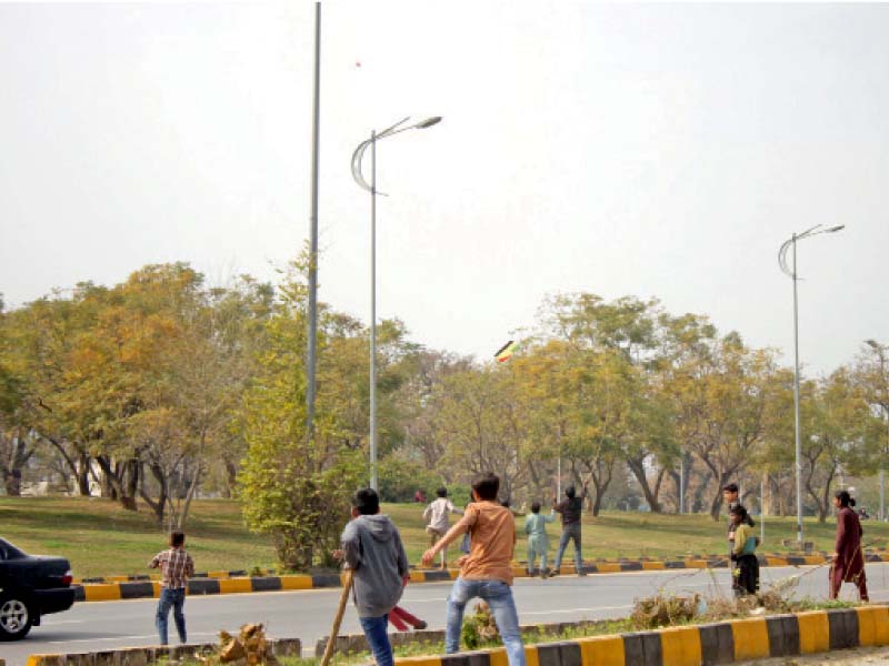 youngsters run after a falling kite on the busy 7th avenue in the federal capital on wednesday a 13 year old boy was injured after he fell from his roof while flying a kite in rawalpindi photo online