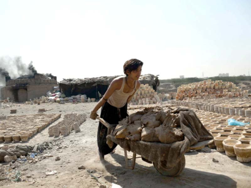 a young boy pushes a cart loaded with clay pots in karachi with the scorching sun beating down his back photo anadolu agency