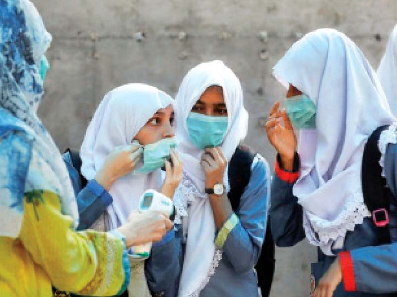 girls adjust their masks before entering a school in karachi schools will reopen on august 23 subject to covid 19 sops 50 per cent attendance and inoculation photo file