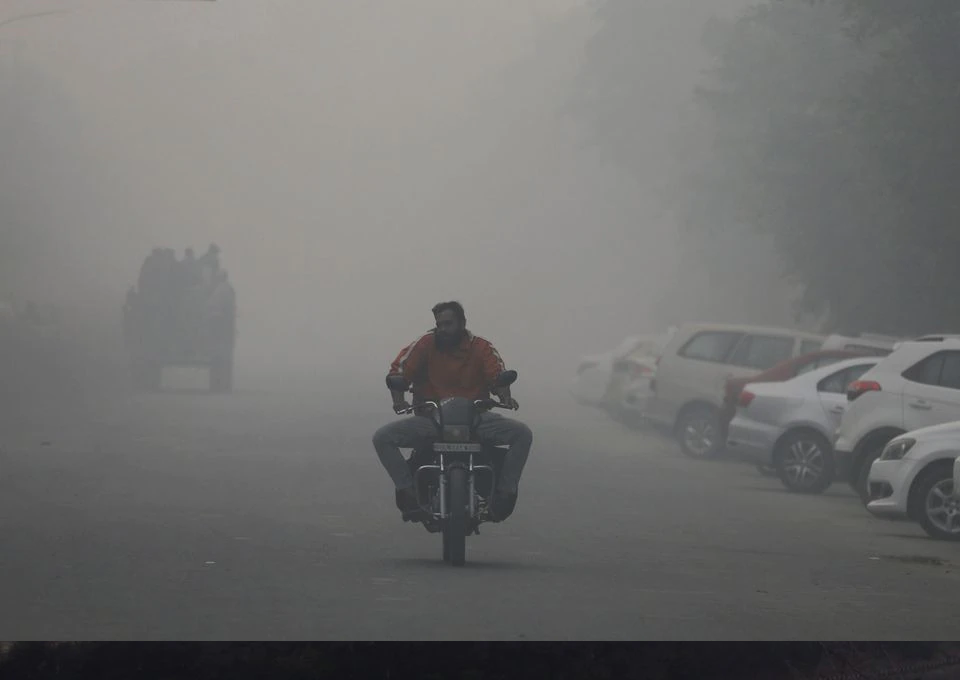 A man rides a motorbike along a road shrouded in smog in Noida, India, November 5, 2021. REUTERS