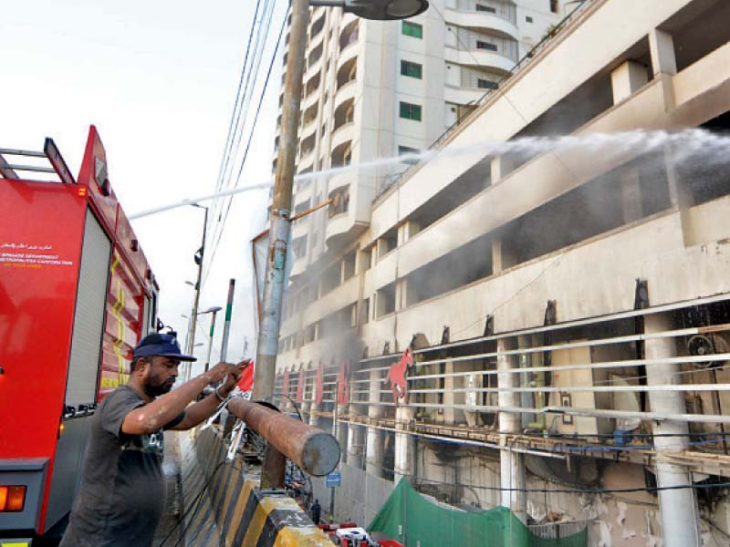 a fireman stands by the fire engine spraying water on the mezzanine floor of the building where fire erupted in the warehouse of a departmental store housed in the basement photo jalal qureshi express