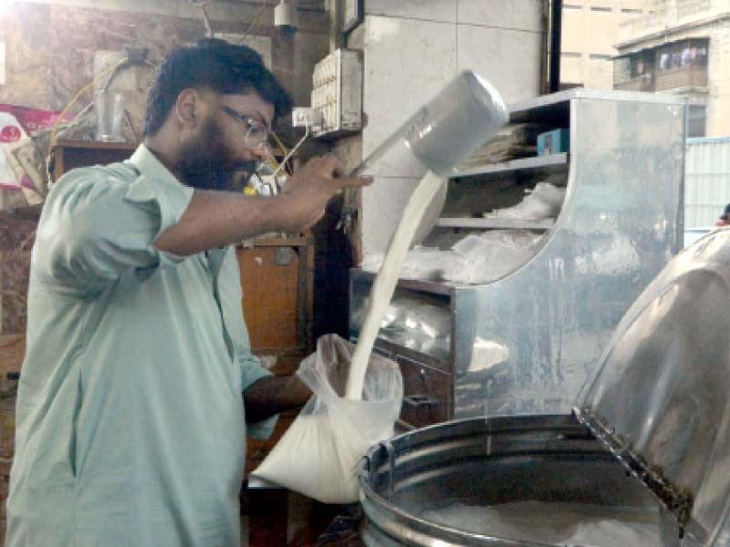 a shopkeeper pours milk for a customer as dairy traders increased the prices of white commodity again on monday photo express