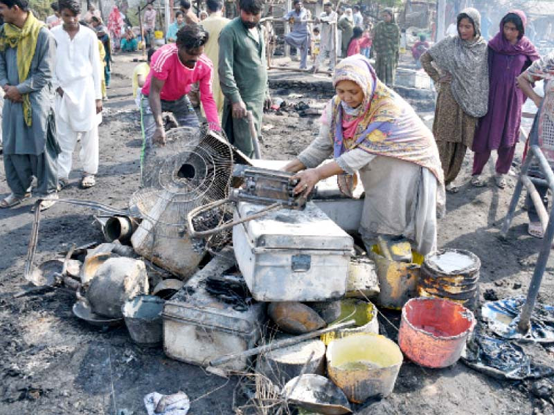 a woman salvages her household items after a blaze swept through a slum in malir destroying over 150 shanties photo online