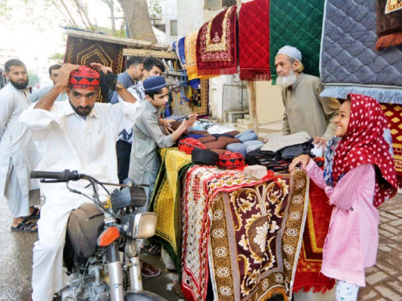 a man tries a cap from a roadside vendor at a neighbourhood in karachi photo jalal qureshi express