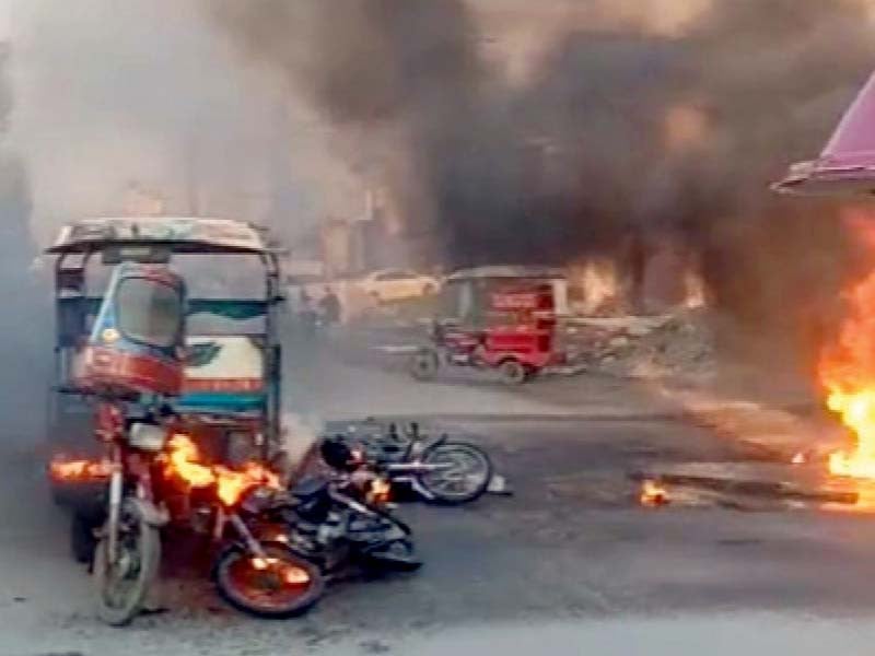 a partially burnt motorcycle lies alongside an auto rickshaw as a fire from the transformer rages photo express