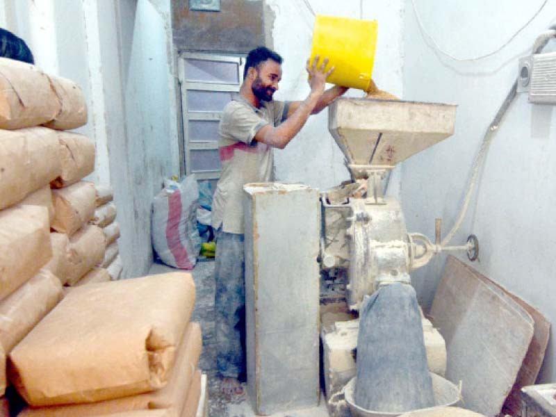 a worker puts wheat in a machine to make flour at a shop in a karachi neighbourhood photo jalal qureshi express