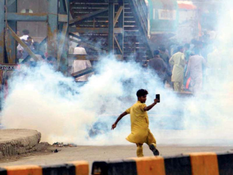 a youth makes a cellphone video during the teargas shelling by police at a protest against power outages in lyari photo ppi