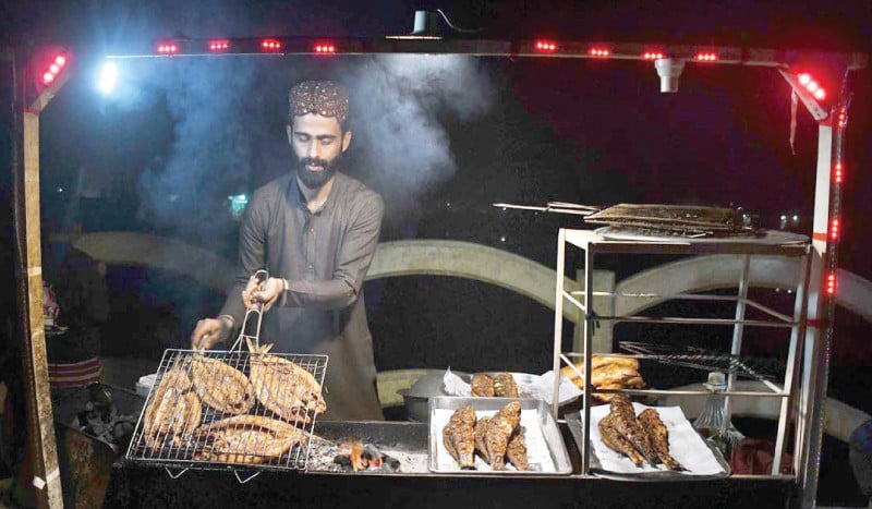 a vendor sells fish along a street in larkana photo app