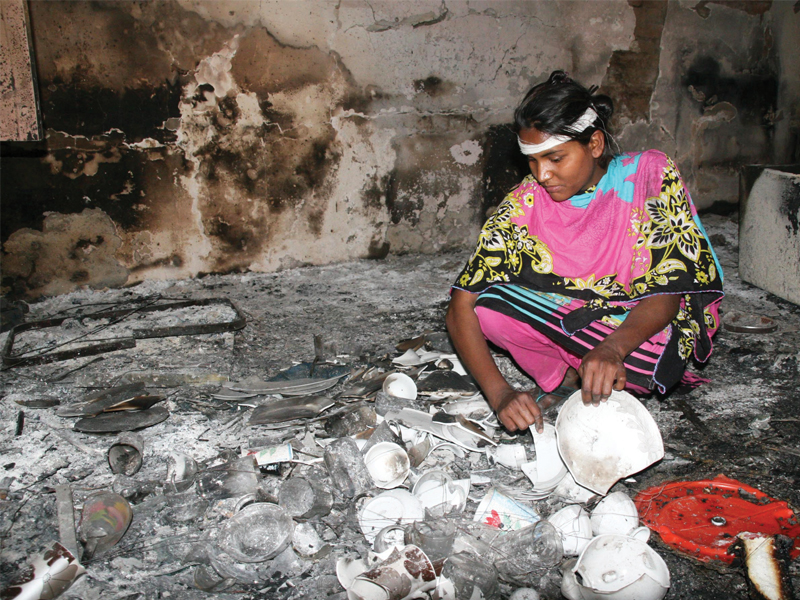 a woman rummages through broken house ware in badami bagh photo shafiq malik express
