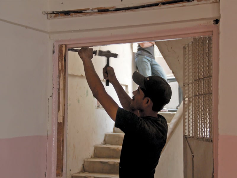 a man tries to remove the wooden frame of a door using a chisel and a hammer the flat is one of the 48 to be torn down after being declared unsafe by the karachi building control authority photo ayesha mir express