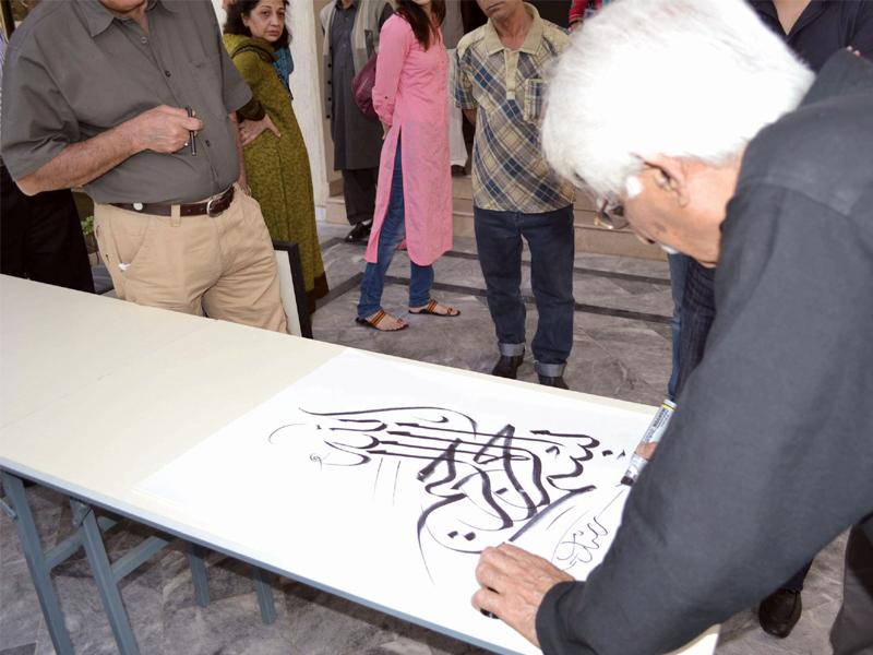 a painting by shehzad mughal left and an artist explaining her work to the audience at the fair on sunday noted calligrapher rasheed butt doing calligraphy photo express