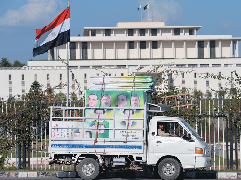 an egyptian flag flutters as a driver parks a mini truck carrying welcoming banners in front of the presidency on sunday photo afp